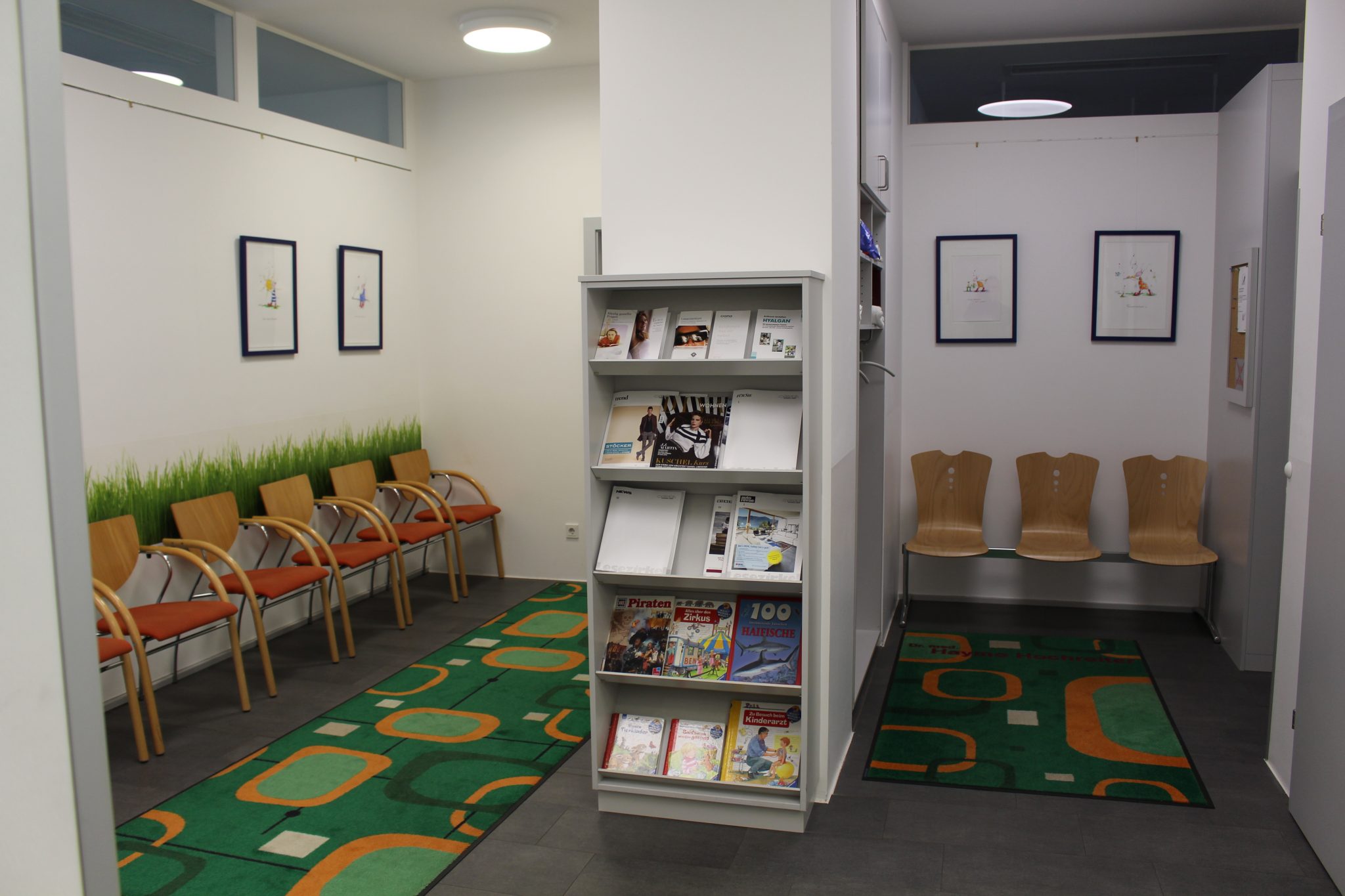 Wartebereich mit Sitzgruppe, Graswanddekoration und Zeitschriftenregal in der Ordination Linz